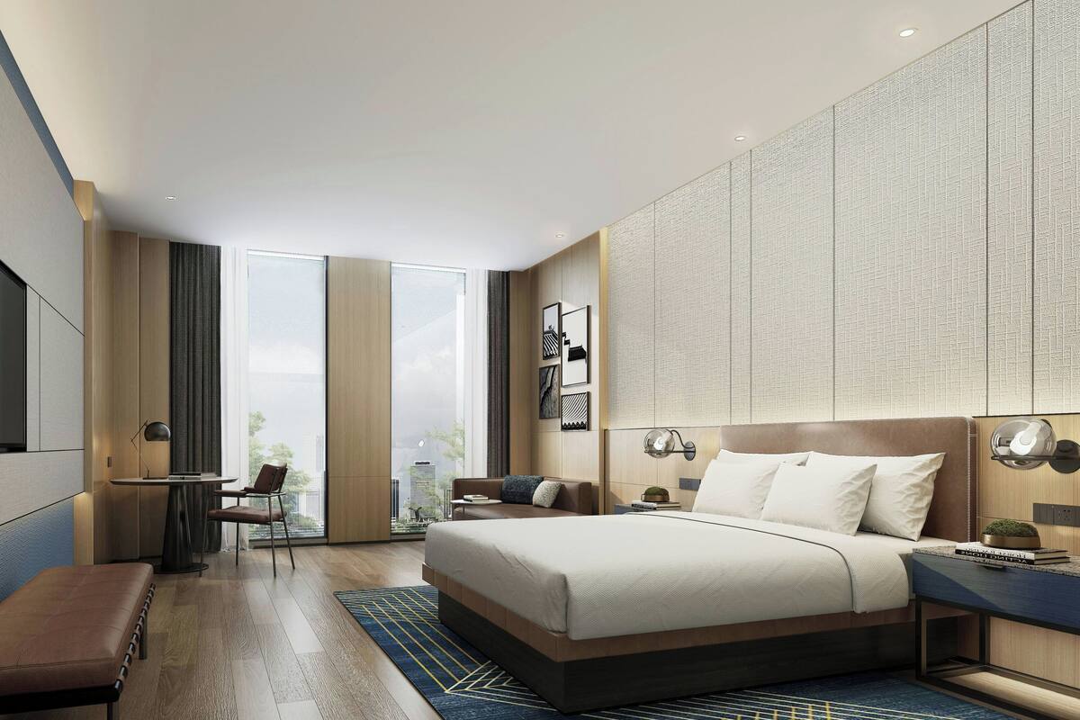 A modern hotel room with a large bed, a desk, and a seating area.