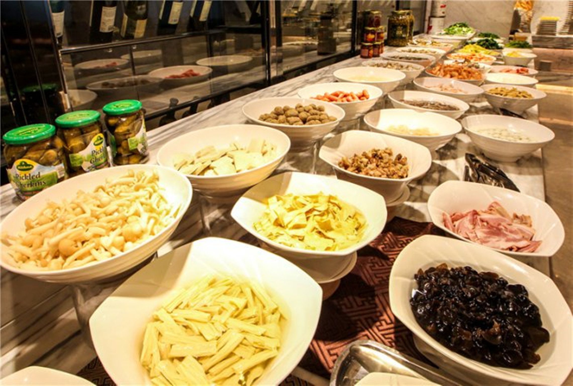 Buffet amb diferents plats, incloent verdures en vinagre, pasta i carns.