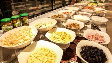 Buffet amb diferents plats, incloent verdures en vinagre, pasta i carns.