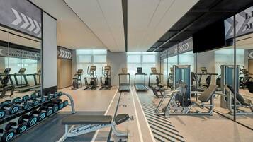 A gym with treadmills, weight machines, and dumbbells.