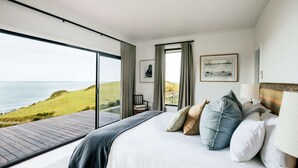 Une chambre avec un grand lit, une vue sur la mer et une terrasse en bois.