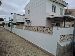 A white building with a stone-paved entrance, a decorative fence, and a sign indicating a height restriction.