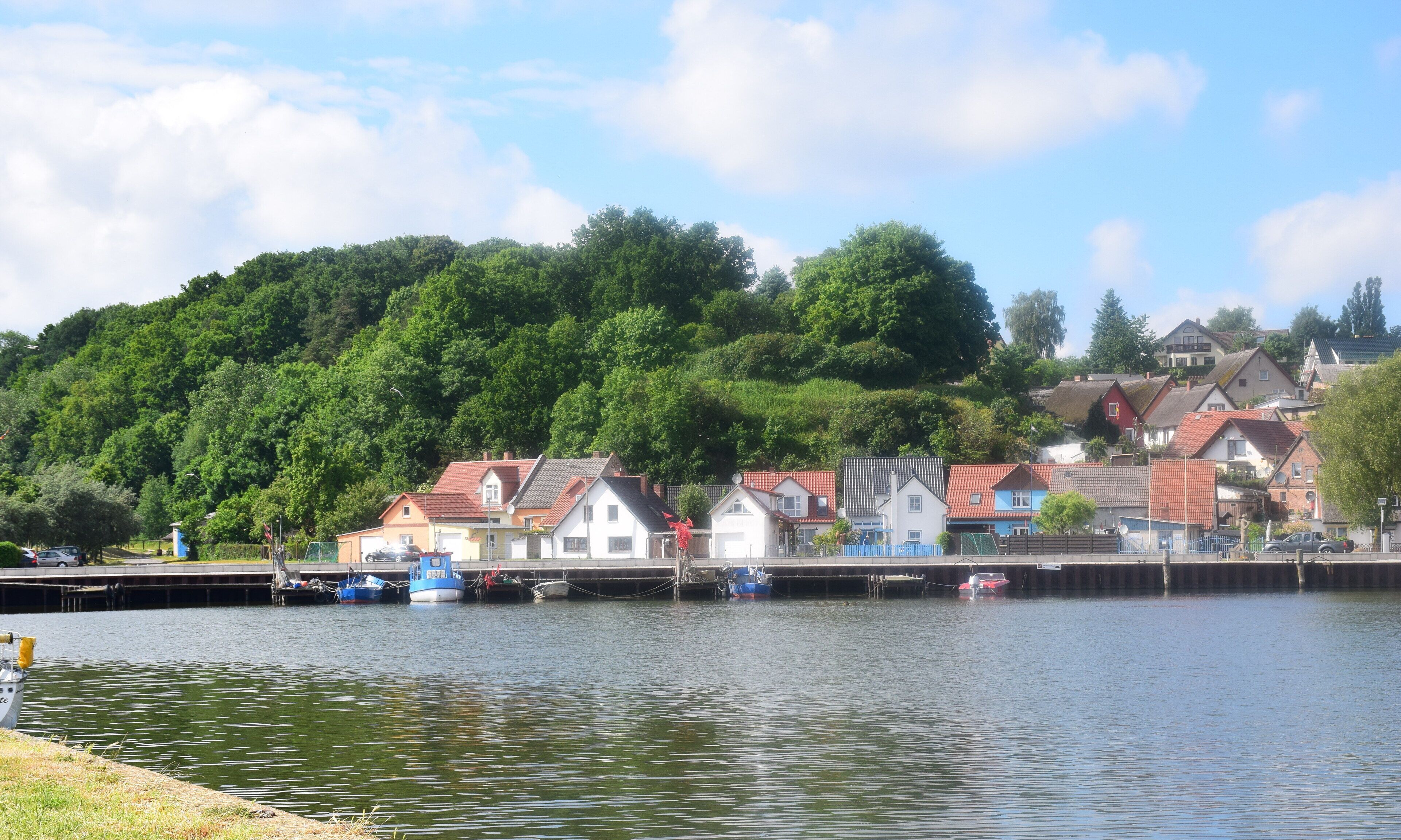 A lakeside view with houses and a dock with boats.