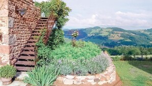Una escalera de piedra conduce a un jardín con vistas a colinas onduladas.