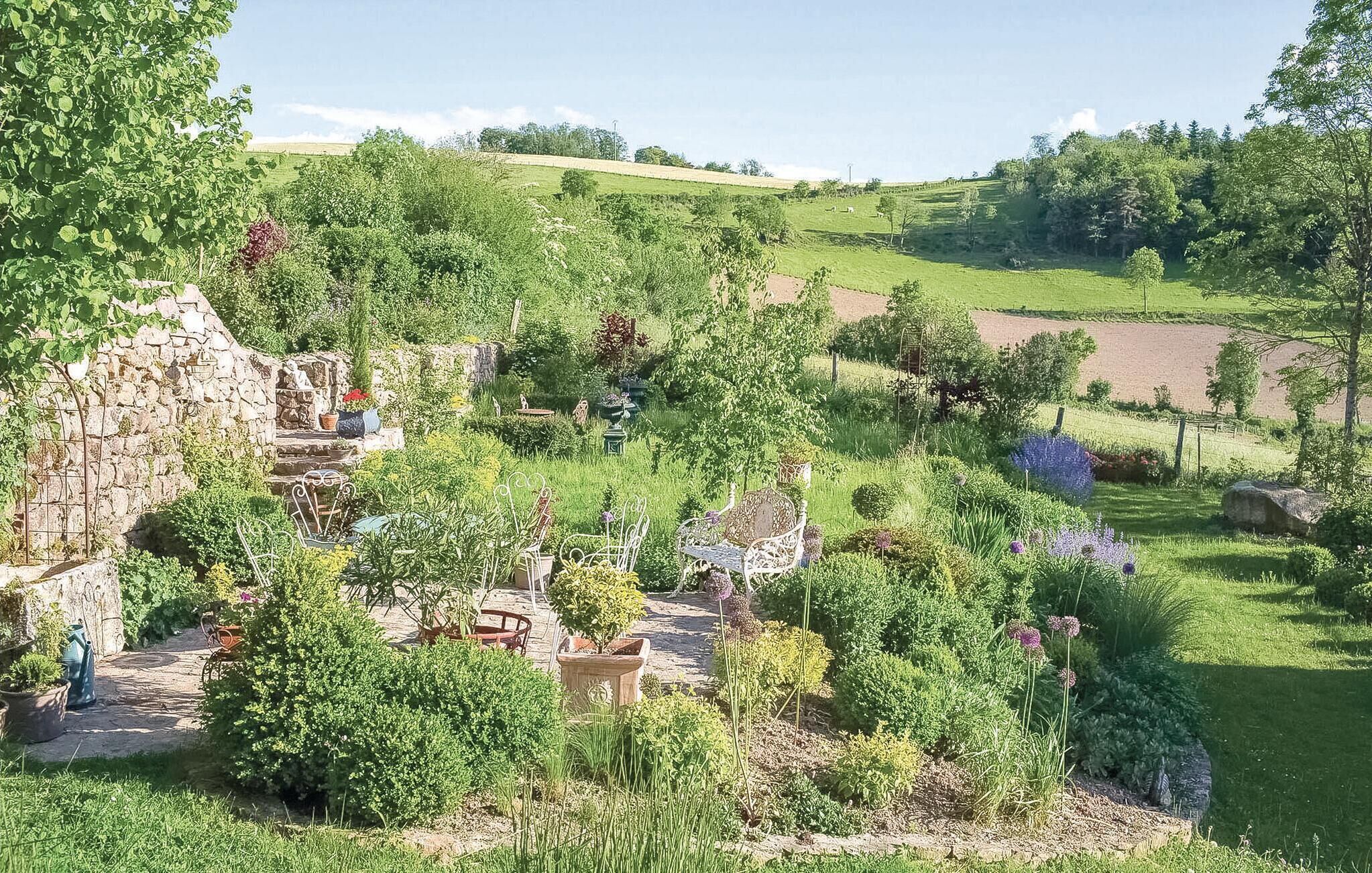 A garden with stone structures, seating areas, and a variety of plants.