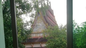 A balcony with a view of a temple, a table, and chairs. - AO Apartment (Vientiane)
