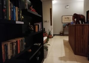 A room with a bookshelf filled with books, a wooden reception desk, and a framed picture on the wall.