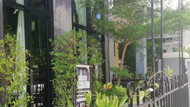 A restaurant with a covered outdoor seating area, a signboard, and potted plants. - AO Apartment (Vientiane)