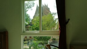 A room with a window overlooking a traditional building with a pointed roof. - AO Apartment (Vientiane)