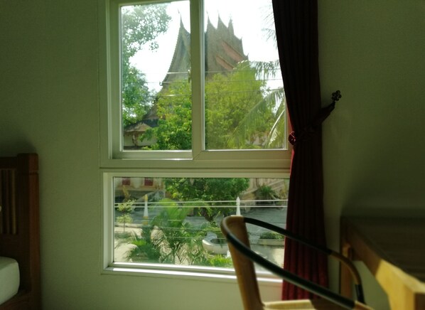 A room with a window overlooking a traditional building with a pointed roof.