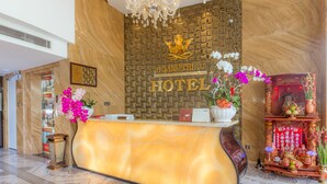 A hotel reception desk with a marble counter, a golden crown emblem, and a traditional altar with offerings. - Hoang Trieu Hotel (Ho Chi Minh City)