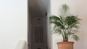 Eine Treppe mit einem Blumentopf rechts, die zu einer Tür mit einem geometrischen Wandbild führt.