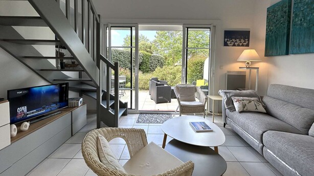 A modern living room with a TV, sofa, and wicker chairs. - 3-bedroom vacation home with heated pool 6 beds (L'Aiguillon-sur-Vie)