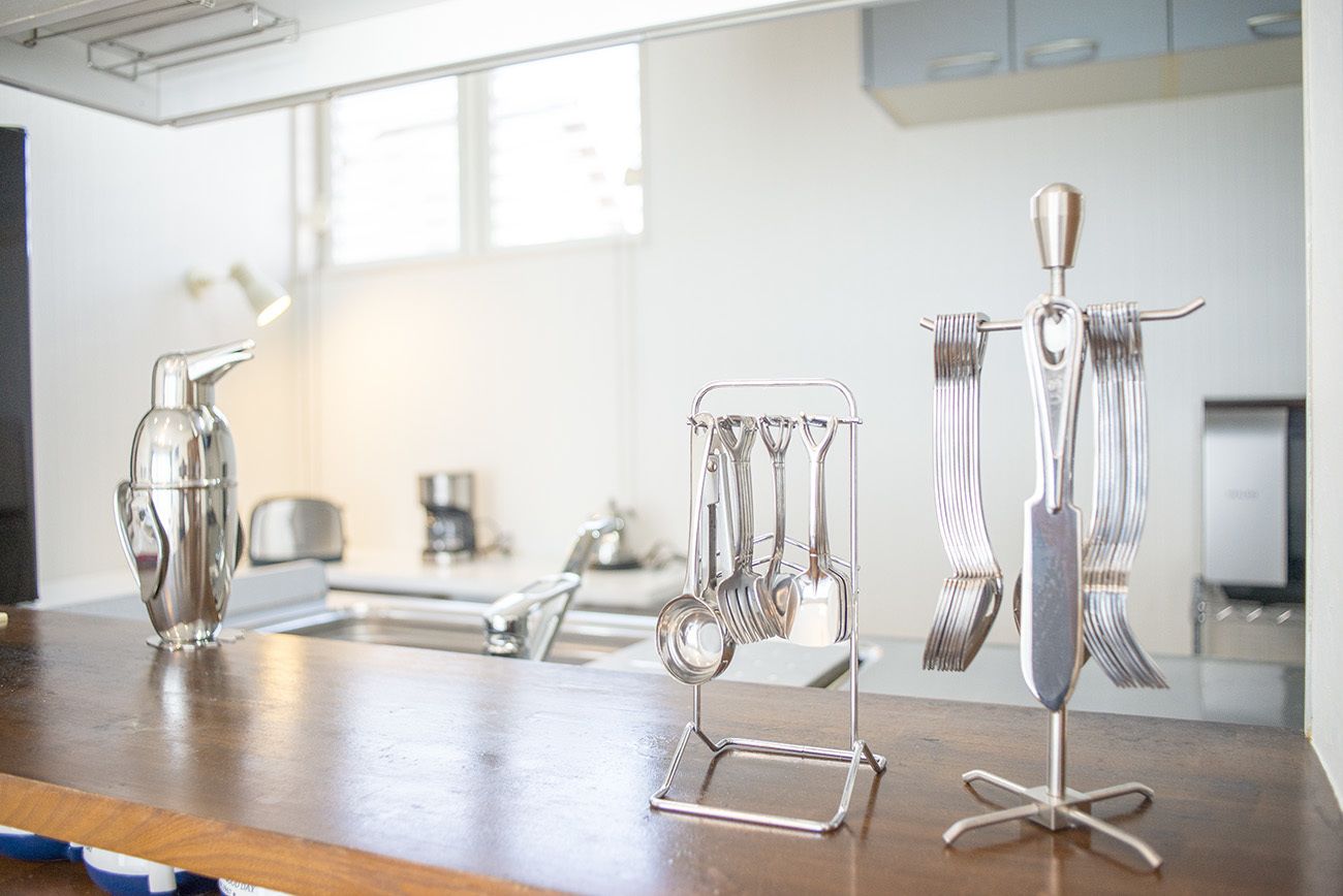 A kitchen with a wooden countertop, a metal utensil holder, and a hanging utensil rack.