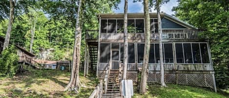 A wooden deck leading to a cabin surrounded by trees.