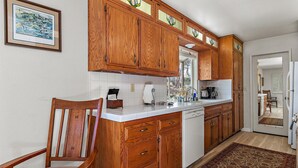 Une cuisine avec des meubles en bois, un plan de travail blanc et une chaise.