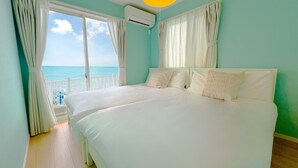 A bedroom with a large bed, white curtains, an air conditioning unit, and a view of the sea. - Private Villa Kin1 with ocean view and BBQ (Kin)