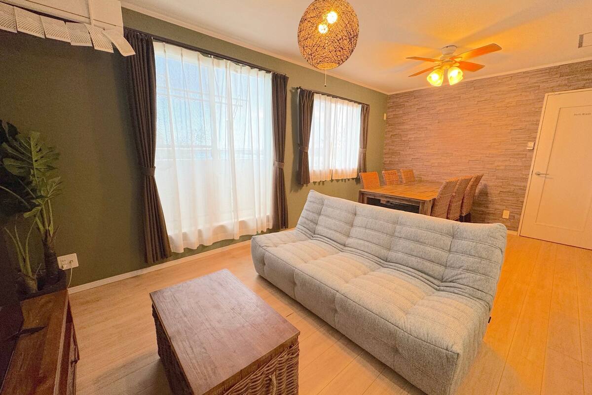 A living room with a sofa, a wooden coffee table, and a ceiling fan.