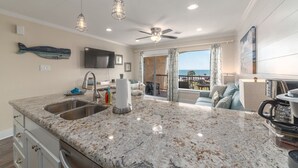 A kitchen with granite countertops, stainless steel appliances, and a ceiling fan. - New Heated Pool & HOT tub! Close Ocean Views! (Galveston)