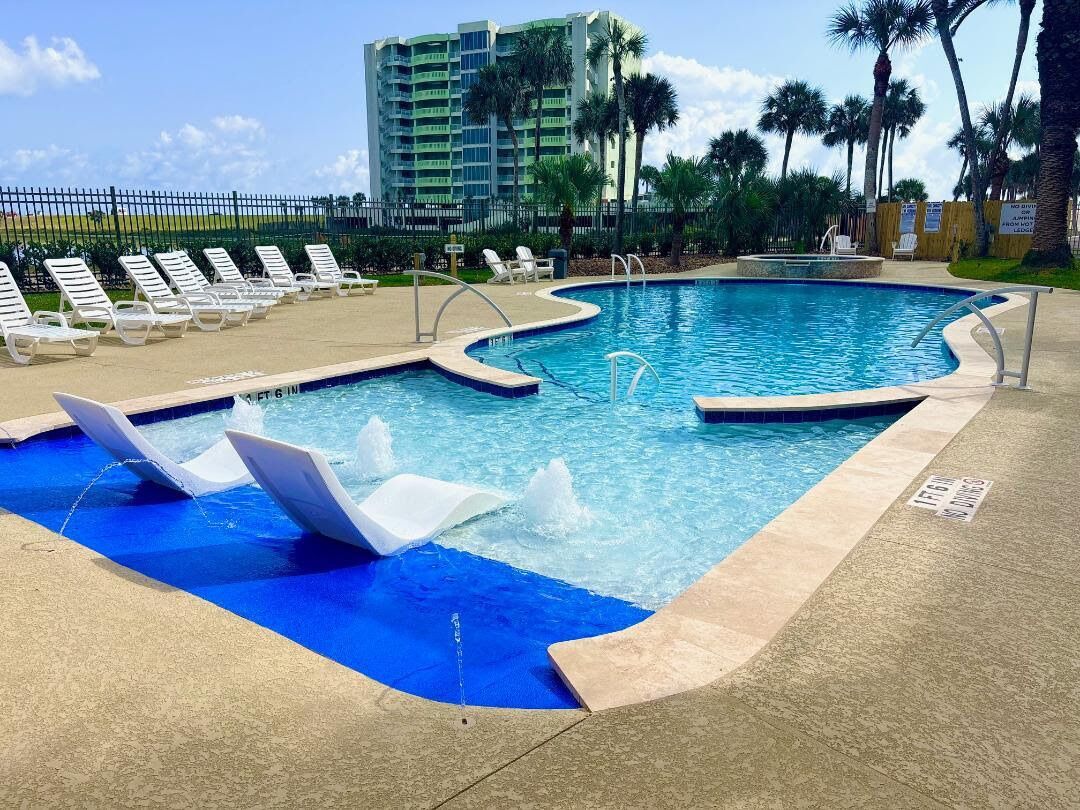 A swimming pool with lounge chairs and a water feature.