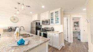 A modern kitchen with granite countertops, stainless steel appliances, and white cabinetry. - New Heated Pool & HOT tub! Close Ocean Views! (Galveston)