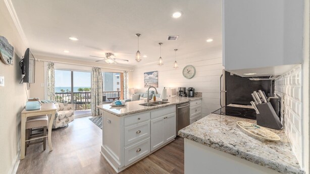 A modern kitchen with a central island, a dining area with a view, and a balcony. - New Heated Pool & HOT tub! Close Ocean Views! (Galveston)