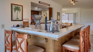 Een keuken met een groot eiland, houten stoelen en een hanglamp.