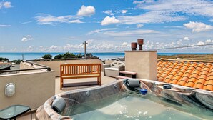 Una terraza en la azotea con hidromasaje, zona de estar y vistas al mar.