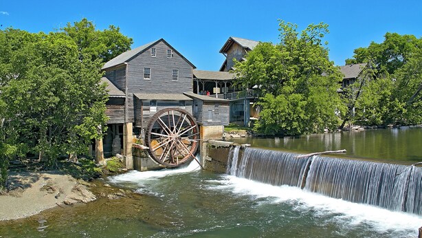 A historic building with a large water wheel and a waterfall.