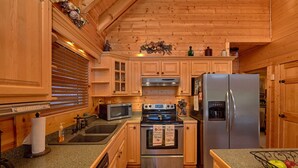 A kitchen with wooden cabinets, a stainless steel refrigerator, a microwave, and an oven.