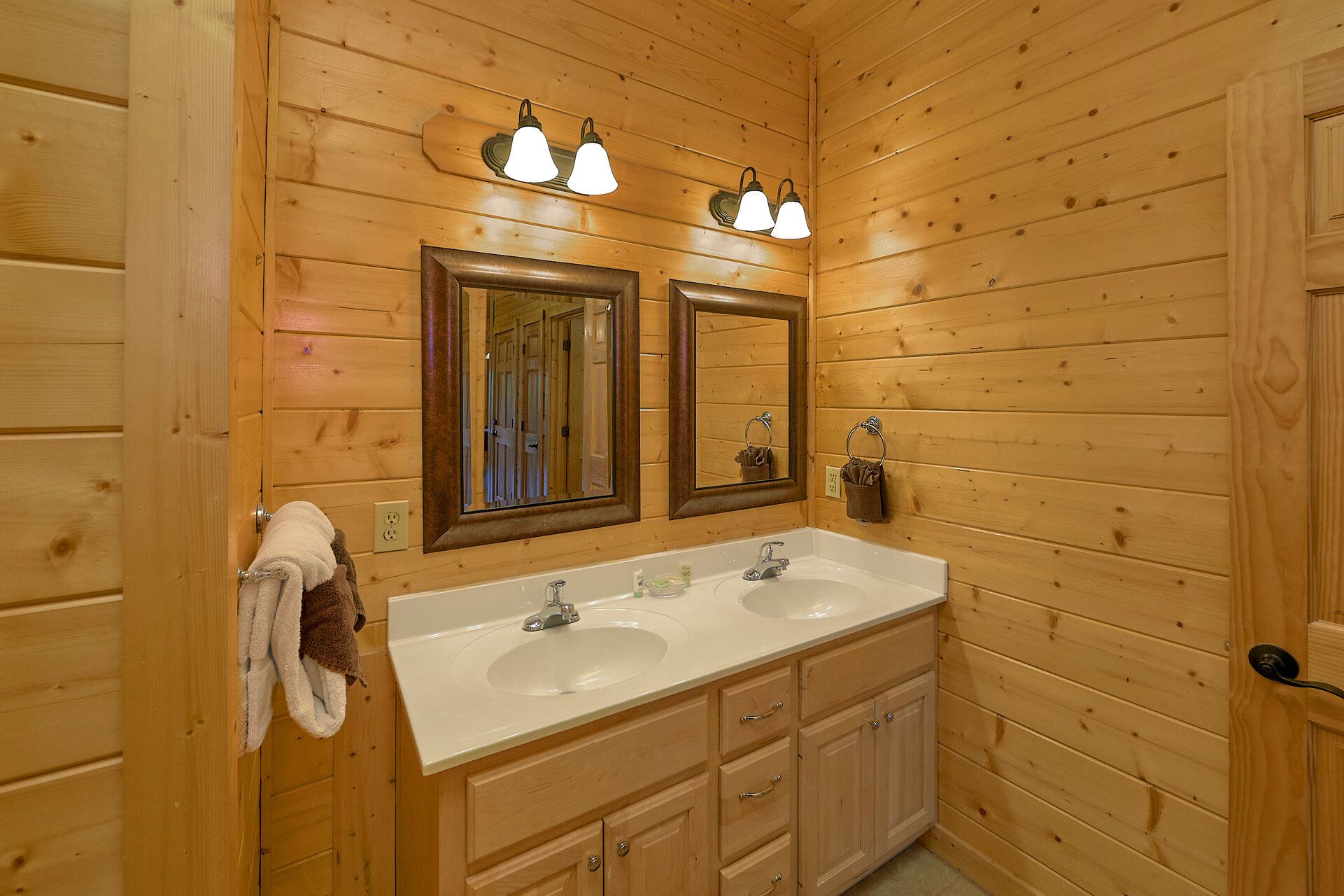 Un baño con paneles de madera, dos lavamanos, un espejo y un perchero para toallas.