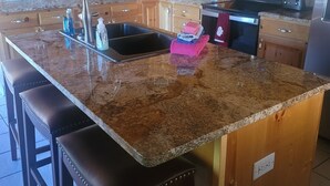 A kitchen with wooden cabinets, a granite countertop, stainless steel appliances, and a bar stool. - Cozy Mountain Retreat / Great For Reunions, Family Retreats,  Room For Tents! (Duck Creek Village)