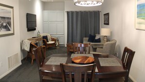 A dining area with a wooden table, chairs, and a chandelier. - 2 Blocks to Ocean - Fall & Winter Special- Gated Building - 5 star reviews (Pismo Beach)