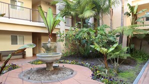 A courtyard with a central fountain, surrounded by a variety of plants and flowers. - 2 Blocks to Ocean - Fall & Winter Special- Gated Building - 5 star reviews (Pismo Beach)