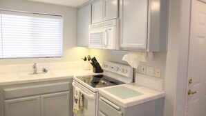 A kitchen with white cabinets, a stove, and a sink. - 2 Blocks to Ocean - Fall & Winter Special- Gated Building - 5 star reviews (Pismo Beach)