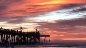A pier extending into the water with a sunset in the background. - 2 Blocks to Ocean - Fall & Winter Special- Gated Building - 5 star reviews (Pismo Beach)