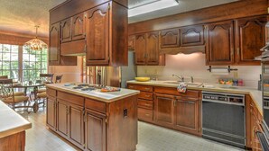 A spacious kitchen with wooden cabinets, a central island, and a dishwasher. - Convenient and spacious 3 br, 1 sofa bed, 2 bath, lg yd, firepit, & patio area. (Asheville)