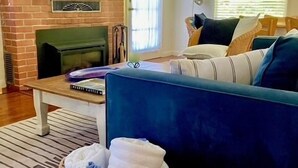 Una sala de estar con un sofá azul, una chimenea, una mesa de madera y una cesta de mimbre.