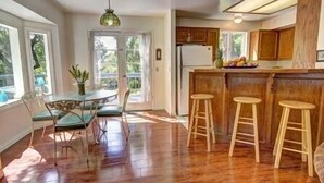 Una cocina con armarios de madera, un refrigerador y una barra con taburetes.