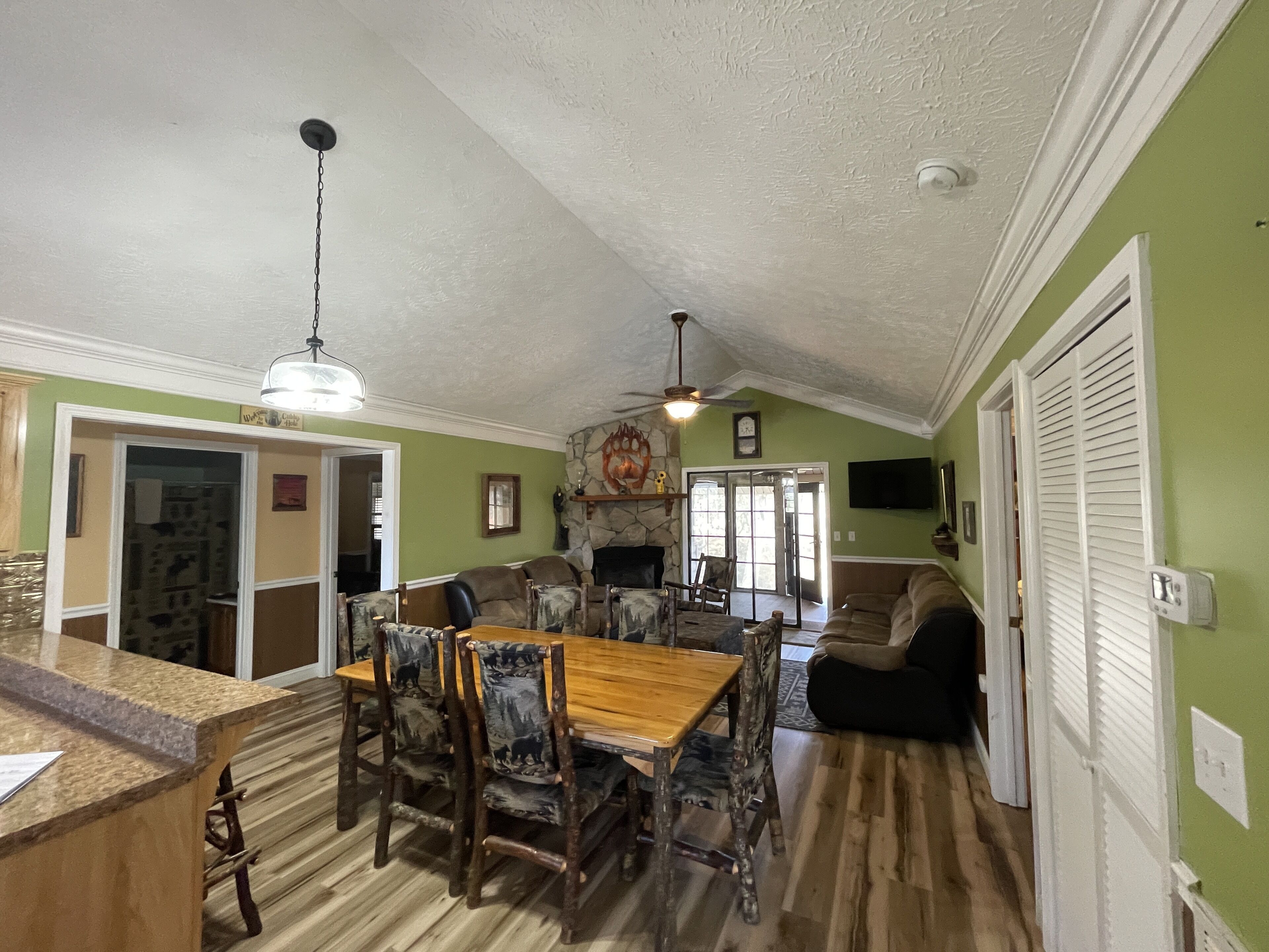A spacious living room with a fireplace, a dining area with wooden furniture, and a kitchen with a granite countertop.