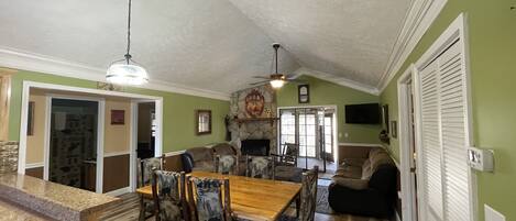 A spacious living room with a fireplace, a dining area with wooden furniture, and a kitchen with a granite countertop.