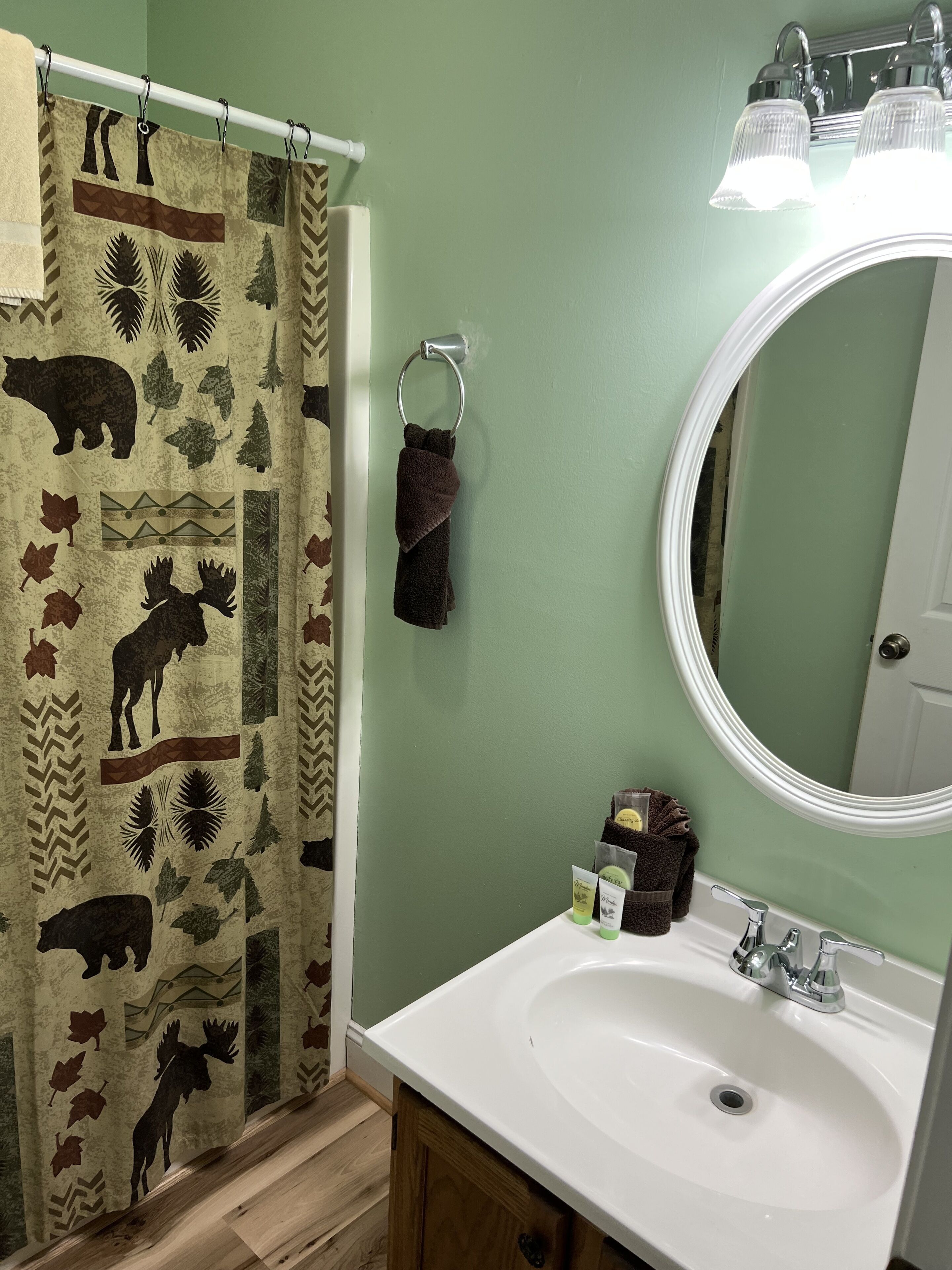 Een badkamer met een wit wastafel, een spiegel en een douchegordijn met dierenprint.