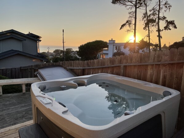 A hot tub with a wooden deck and a wooden fence in the background.