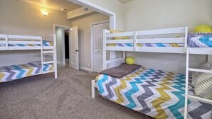 Una stanza con letti a castello, pavimento rivestito di moquette e una porta che dà su un'altra stanza.