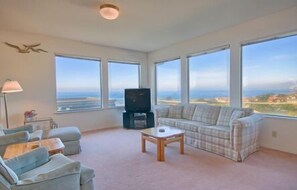 Relax in this spacious living room with a high ceiling and stunning views of the surrounding landscape.