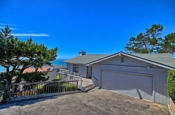 Situated in a coastal area, this single-story home features a garage and a small porch with a railing, perfect for outdoor activities.