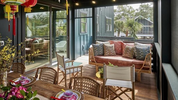 A cozy outdoor seating area with wicker furniture and a cushioned bench, overlooking a garden and a house. - The Fish! Most Unique High-End Luxury Rental w/Private Pool On Folly Beach! (Charleston)