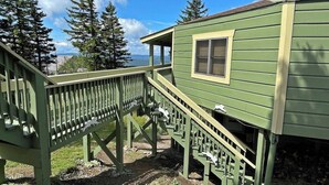 A green wooden house with a porch and a staircase leading to a window. - Adventure Awaits! (Snowshoe)