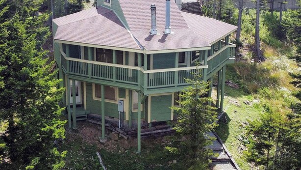 A two-story house with a green exterior, a balcony, and a chimney. - Adventure Awaits! (Snowshoe)