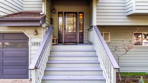 Une maison à deux étages avec un porche à l’avant, un escalier et un garage.